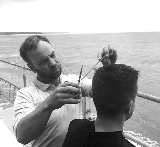 Bruno, cutting hair on the seaside in Porthleven, Cornwall